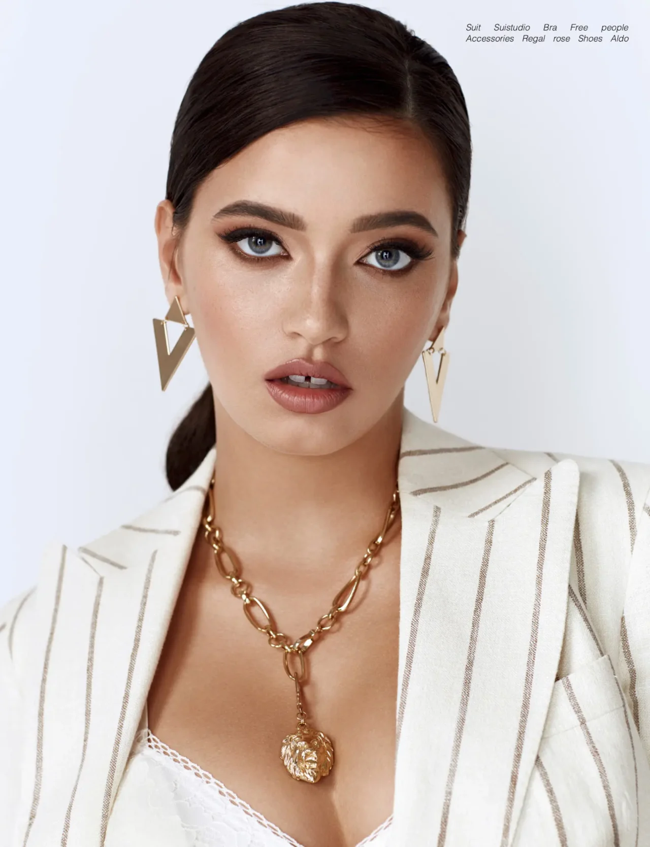 Model in a striped suit and bold gold jewelry