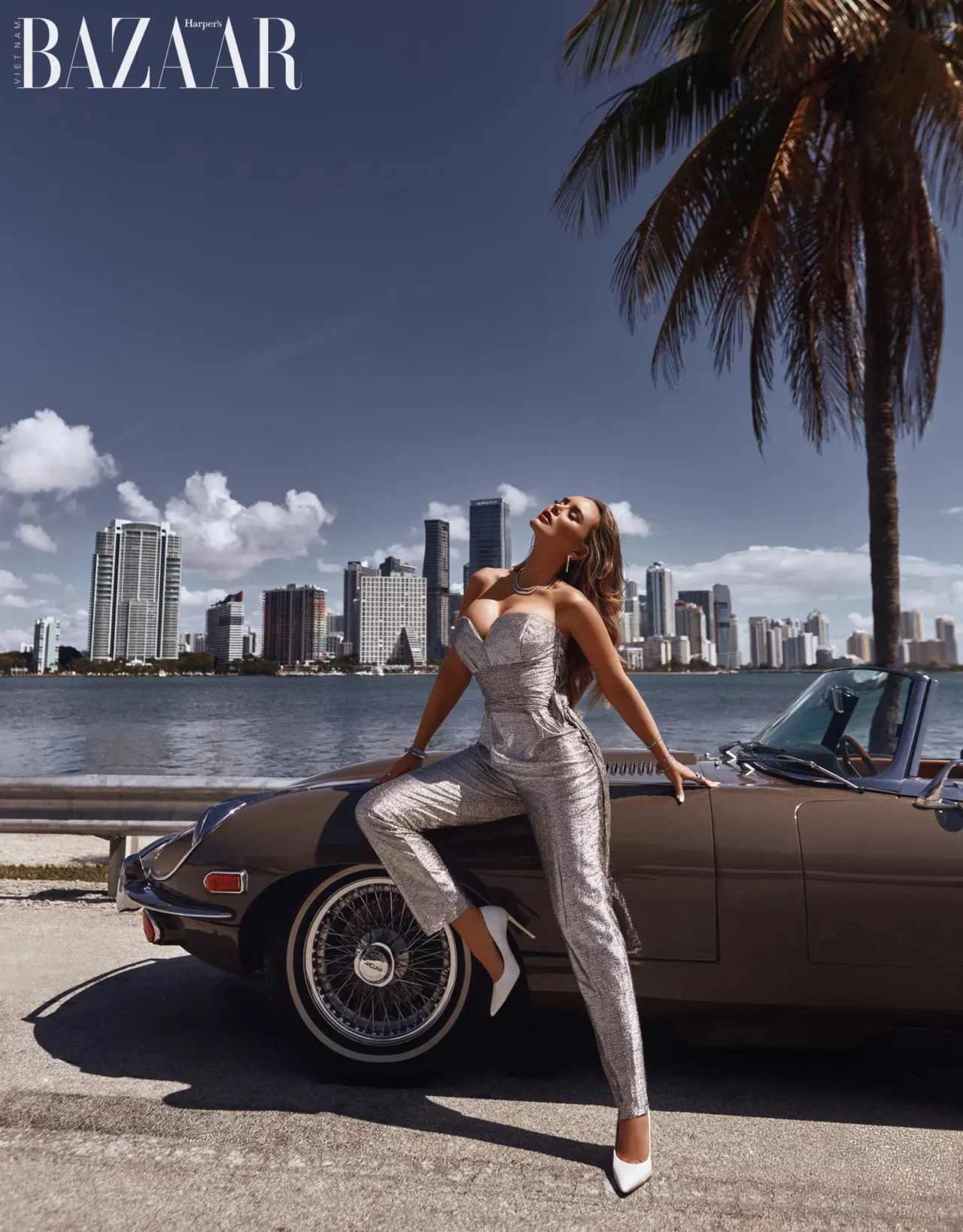 Model posing against classic car with Miami's skyline